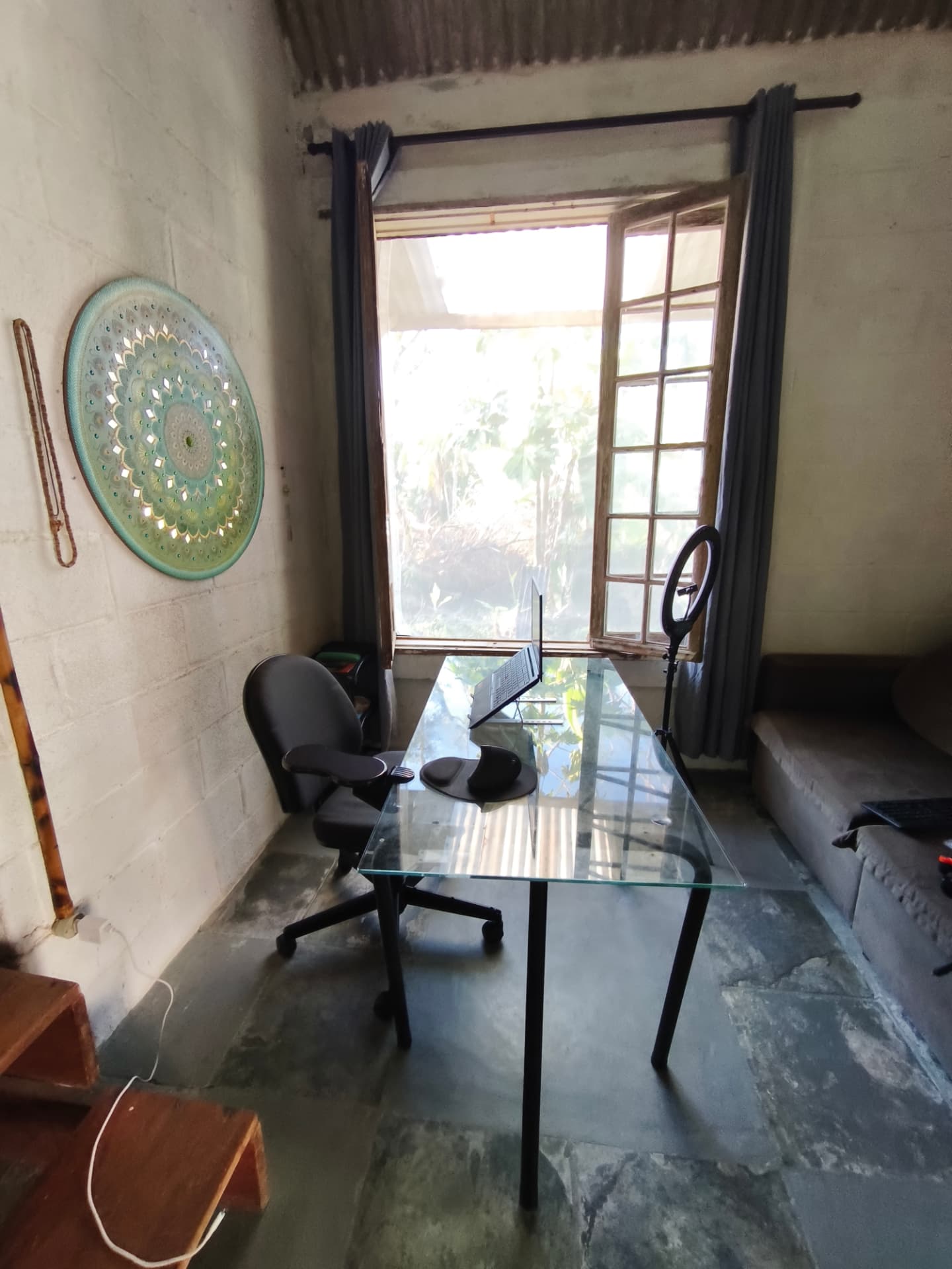Canto de trabalho com mesa de vidro e mandala na parede