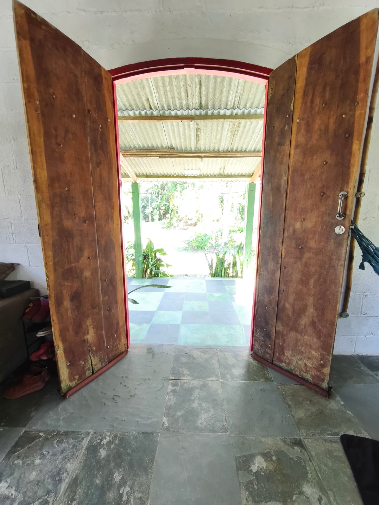 Portas de madeira abertas para a varanda e a mata