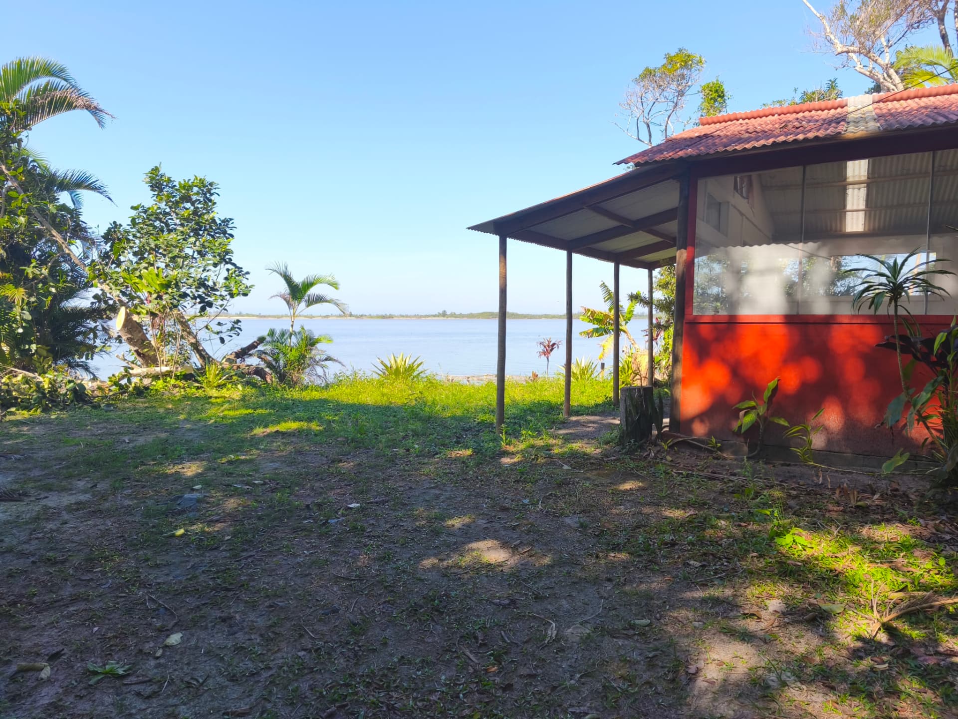 Casa vermelha à beira do rio cercada de verde