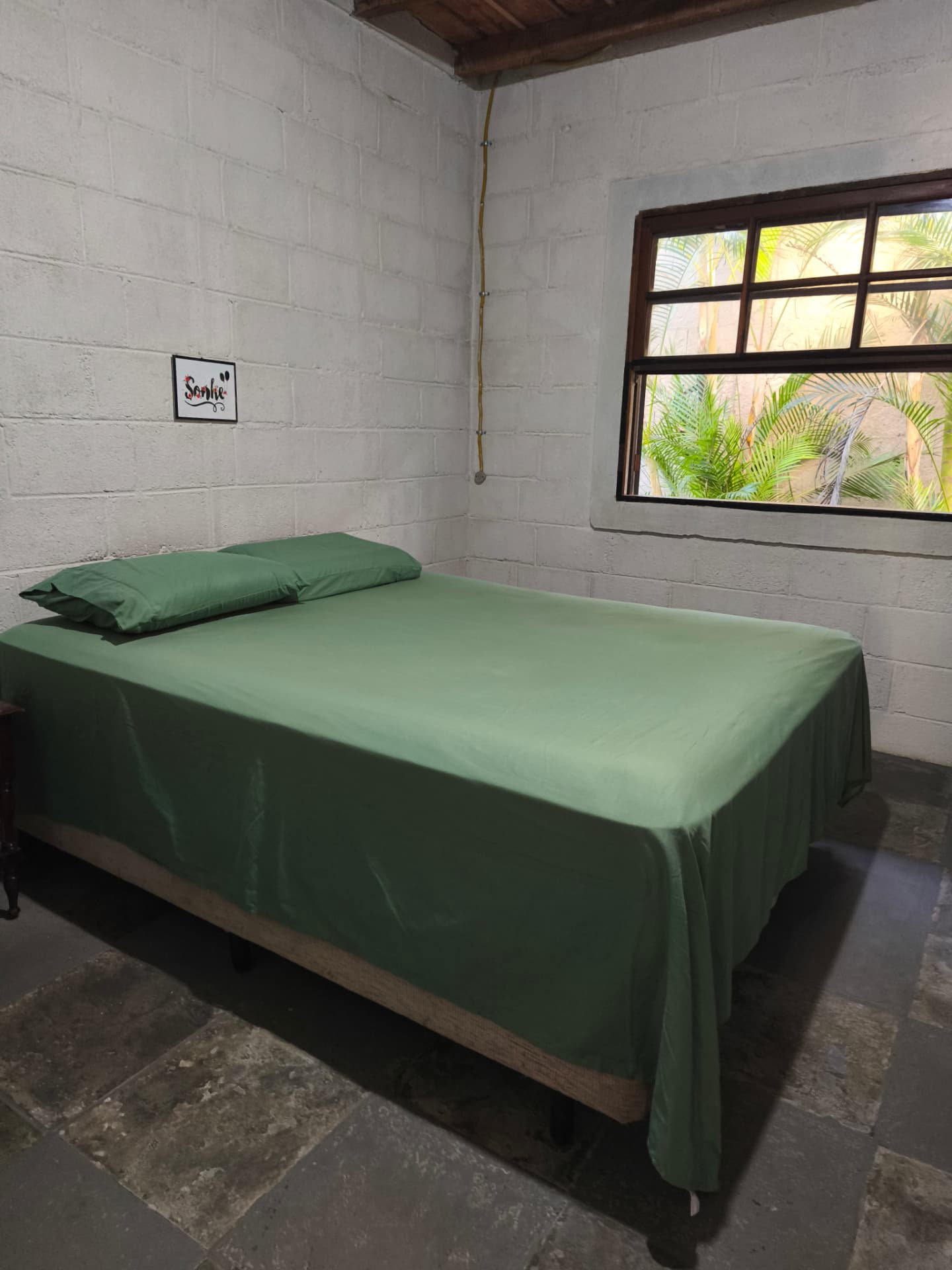 Quarto com cama de casal e janela para a mata