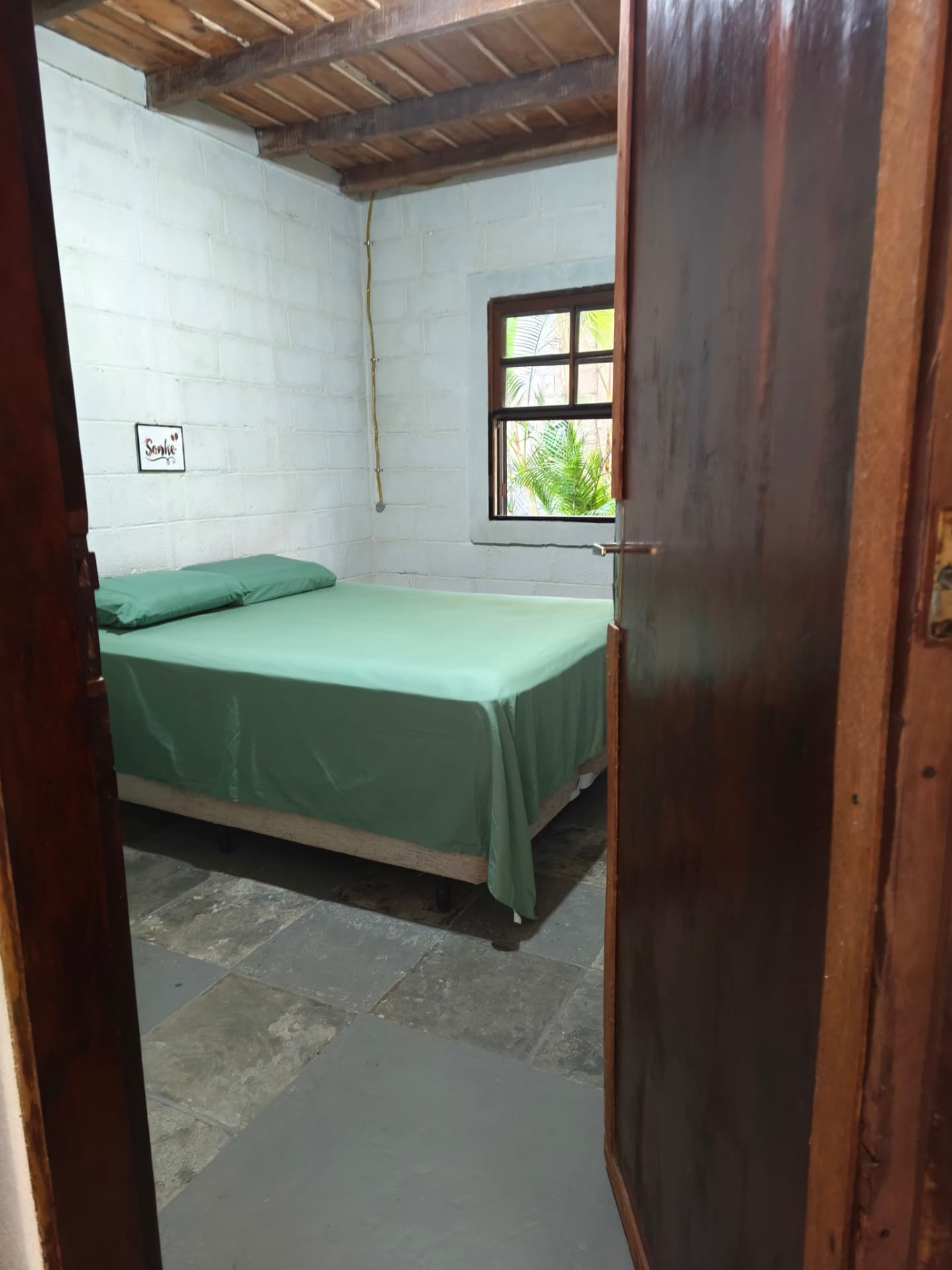 Quarto visto pela porta de madeira, com piso de pedra