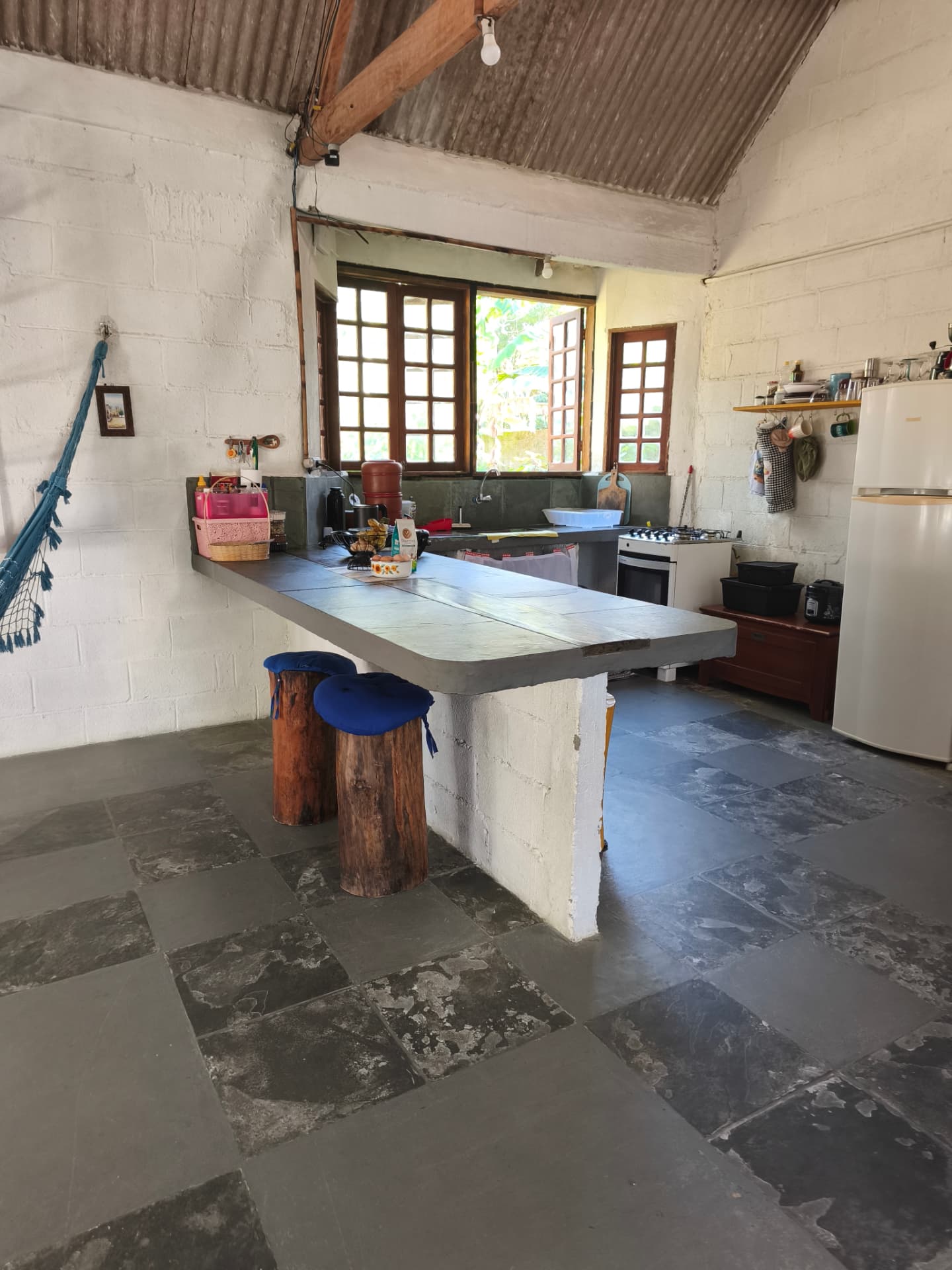 Cozinha compartilhada com mesa de pedra e bancos de tronco